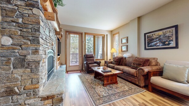 A cozy living room with a stone fireplace, a leather armchair, a sofa, and a coffee table.