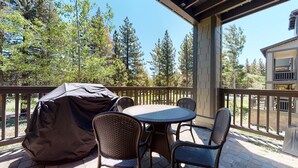 A covered outdoor patio with a round table and four chairs, surrounded by a wooden railing.
