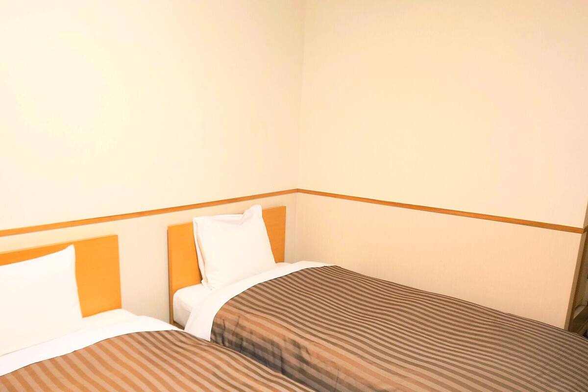 A single bed with a wooden headboard, white pillows, and striped bedding.