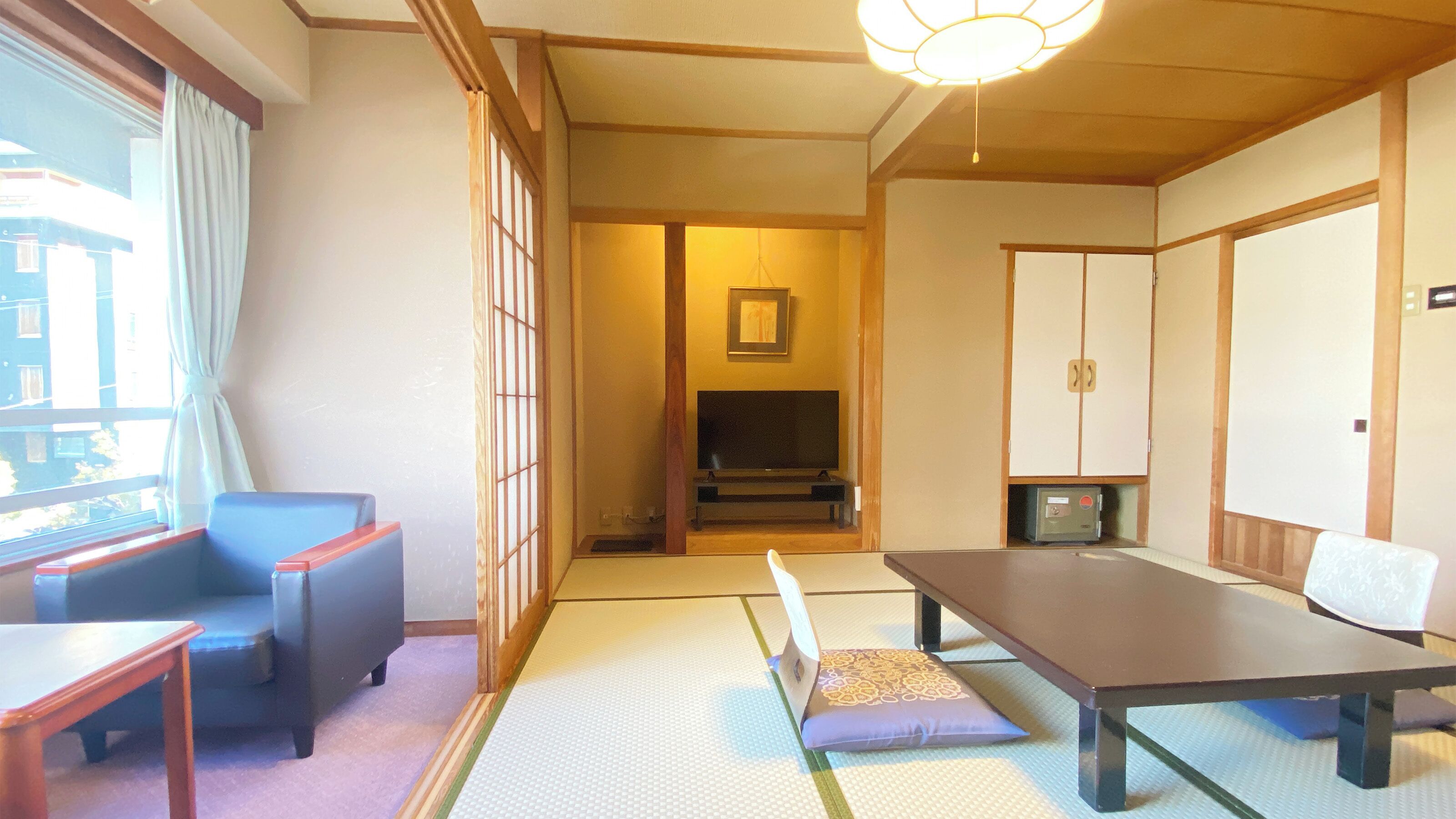 A traditional Japanese room with tatami flooring, a low table, a sofa, and a television.