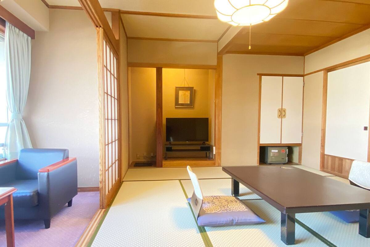 A traditional Japanese room with tatami flooring, a low table, a sofa, and sliding doors.