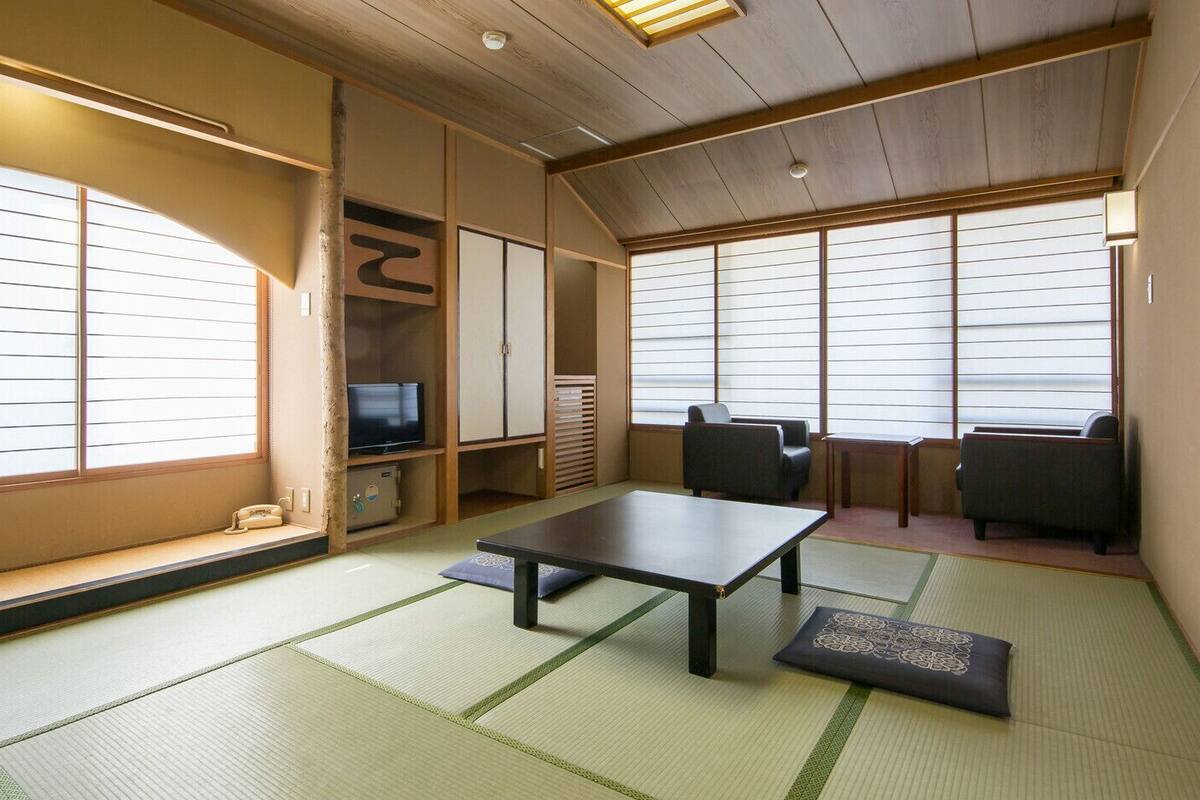 A traditional Japanese room with tatami flooring, a low table, seating, and sliding doors.