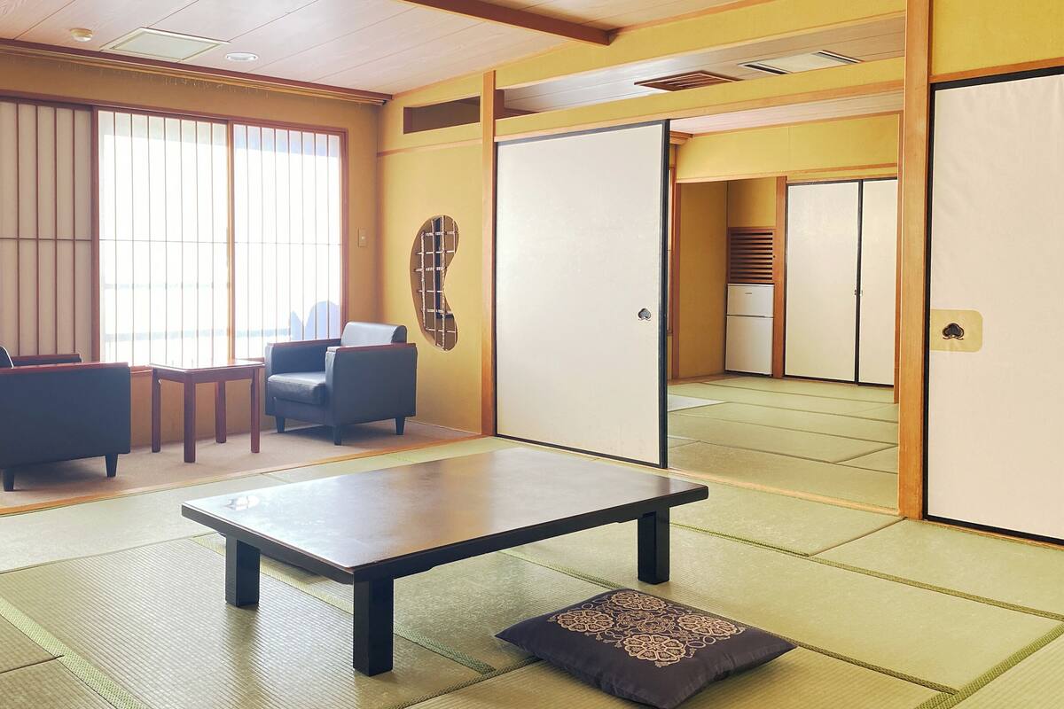 A traditional Japanese room with tatami flooring, a low table, and a sofa.