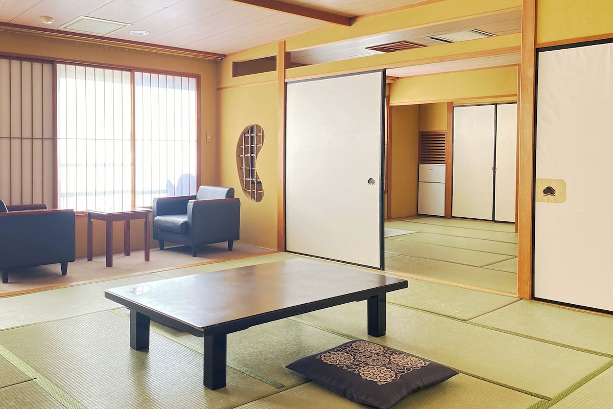 Um quarto japonês tradicional com tatames, uma mesa baixa e um sofá.
