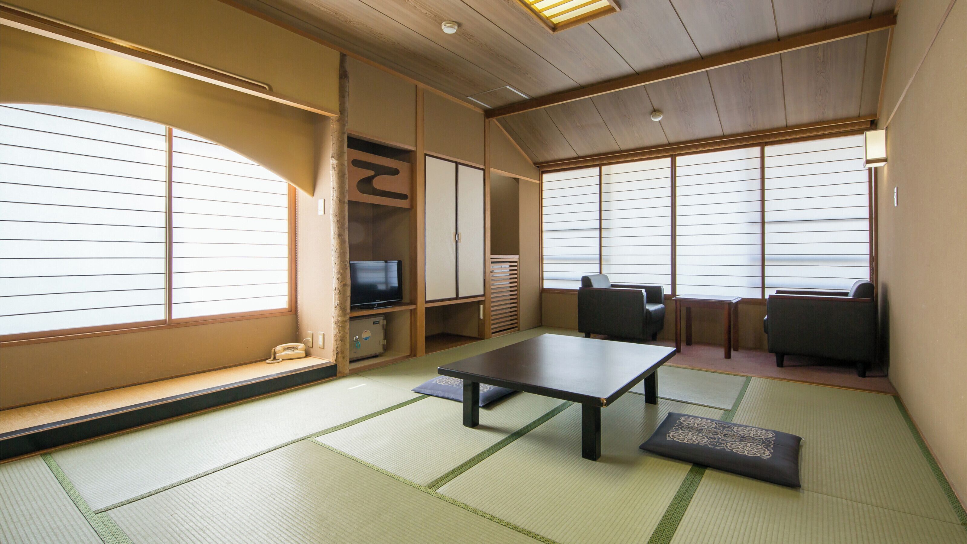A traditional Japanese room with tatami flooring, a low table, seating, and sliding doors.