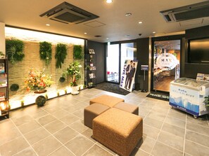 Un vestíbulo con mostrador de recepción, zona de estar y una pared decorada con plantas.