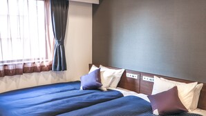 Hotelkamer met een groot bed, twee kussens, een hoofdeinde met bedieningsknoppen en een raam met gordijnen.