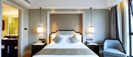 Een hotelkamer met een groot bed, twee nachtkastjes, een stoel, een bureau met een lamp en een spiegel.