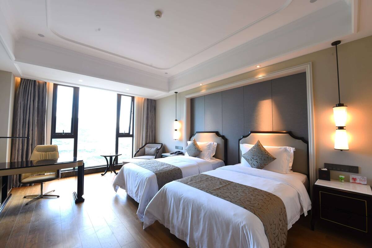 Ein Hotelzimmer mit zwei Betten, einem Schreibtisch und einem Stuhl.