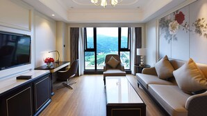 Un salon moderne avec un canapé, une table basse, un téléviseur et une vue sur l’extérieur.