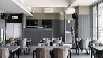 A modern restaurant with grey upholstered chairs and tables, a visible toilet sign, and a Starcongs sign above the counter.