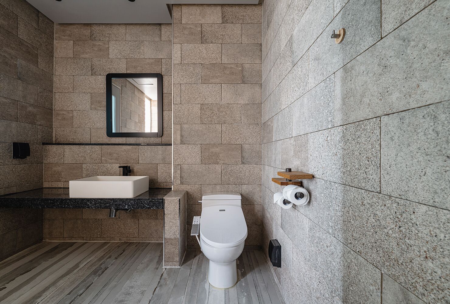 A modern bathroom with a rectangular sink, a toilet, and a mirror on the wall.