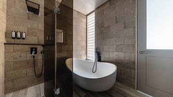 A modern bathroom with a freestanding bathtub, a glass-enclosed shower, and a door with a frosted glass panel.
