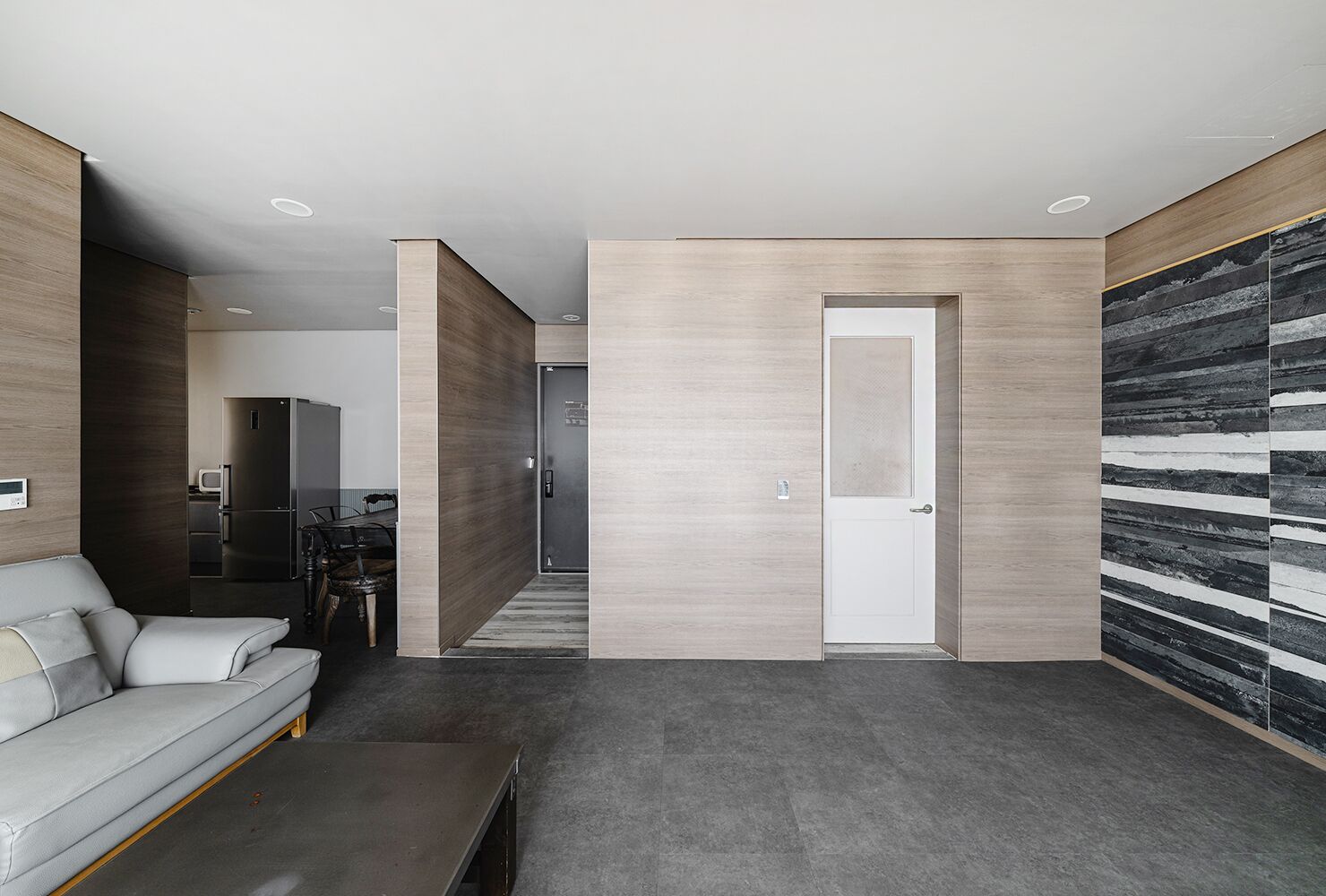 A modern living room with a grey sofa, a coffee table, and a kitchen in the background.