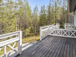 Una terraza de madera con barandas blancas que da vista a un área boscosa.