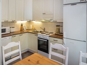 Uma cozinha compacta com armários brancos, micro-ondas, torradeira, pia e fogão.