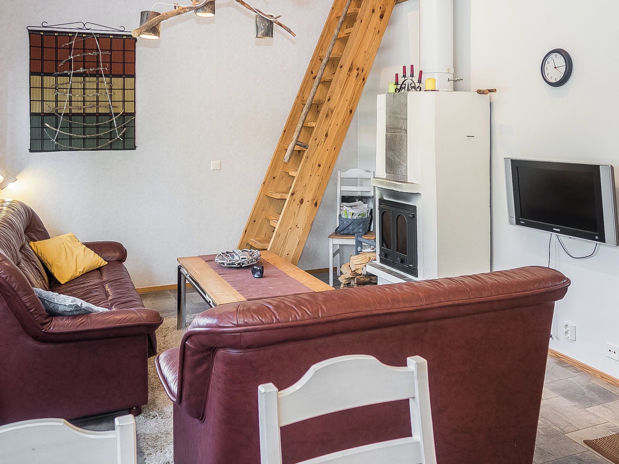 A living room with a sofa, a coffee table, a fireplace, a TV, and a wooden ladder.
