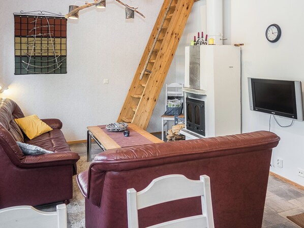 A living room with a sofa, a coffee table, a fireplace, a TV, and a wooden ladder.