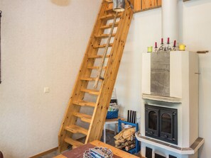A room with a wooden ladder leaning against a wall, a fireplace with a mantel, and a table with items on it. - Onkijantie 7b by Interhome (Kuusamo)