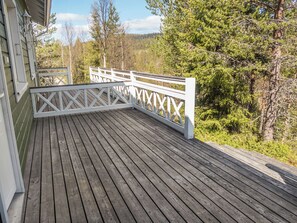 A wooden deck with a white railing, surrounded by trees and a mountain in the background. - Onkijantie 7b by Interhome (Kuusamo)