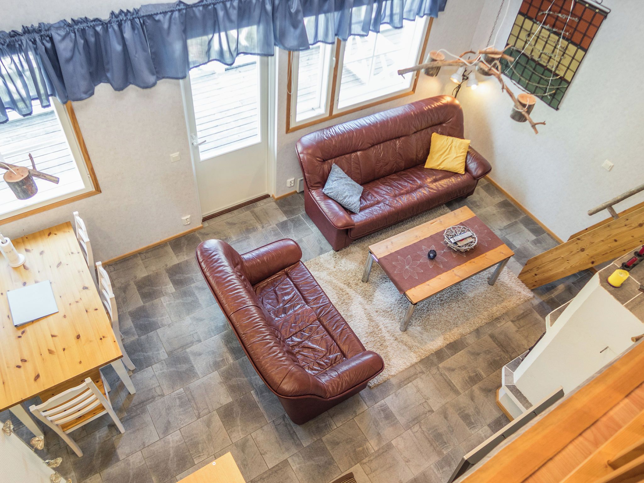 A spacious living area with a brown leather sofa, a wooden coffee table, and a dining table with chairs.