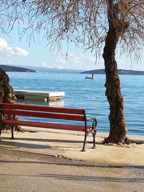 Un banc au bord d’un lac, avec un bateau visible au loin.