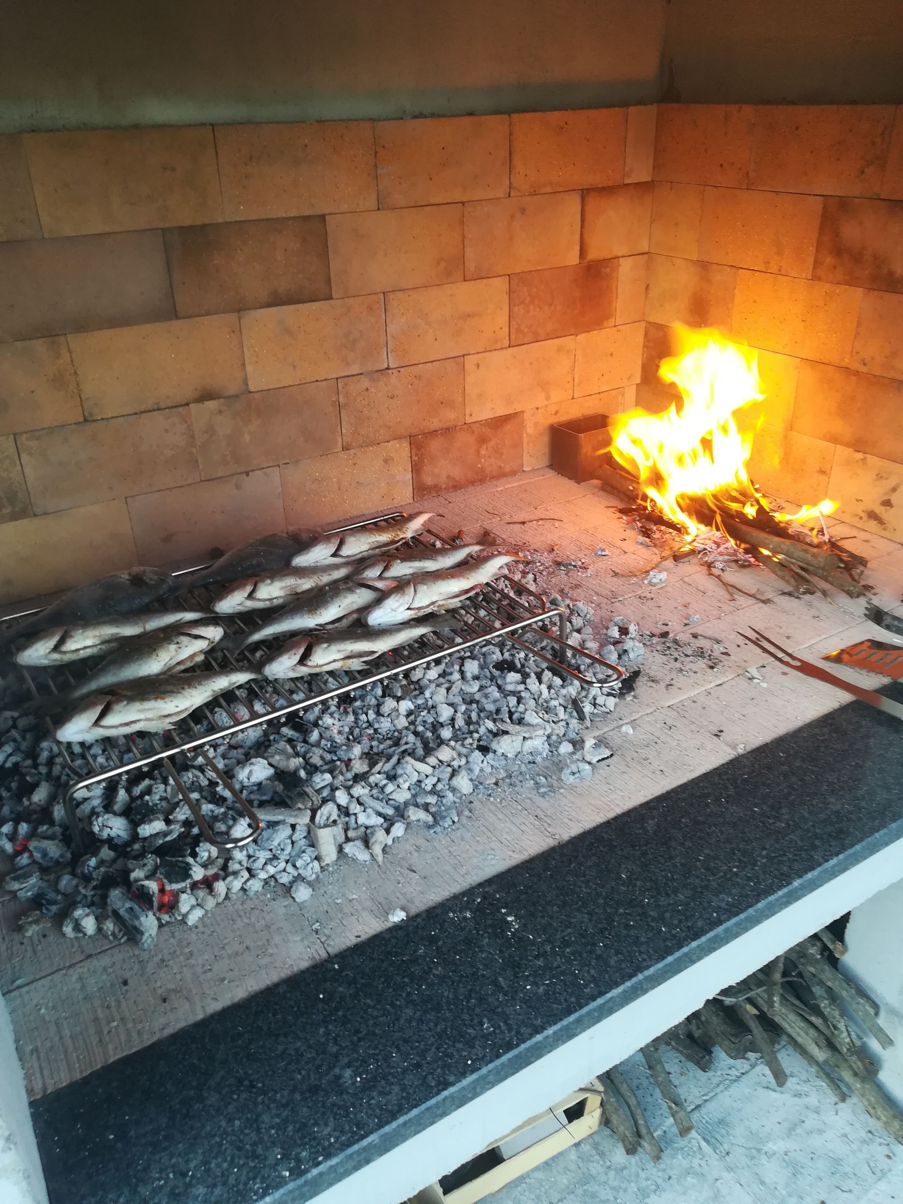 A brick oven with fish being grilled.