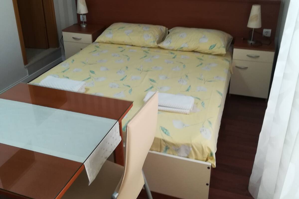Une petite chambre comprenant un lit, des tables de chevet, un bureau et une chaise.