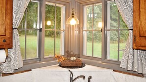 A bathroom with a large window, a sink, and a hanging light fixture. - Driftwood Cottage: Your Gateway to Lake Superior & Apostle Islands (Washburn)
