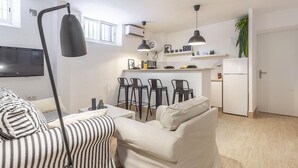 A modern living room with a sofa, a TV, and a dining area with chairs and a kitchen in the background. - ELEGANT DESIGN APARTMENT! 2 BED -SEVILLA- WIFI - 5 PAX (Sevilla)