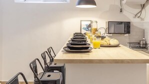 A modern kitchen with a central island, black chairs, a microwave, and a TV mounted on the wall. - ELEGANT DESIGN APARTMENT! 2 BED -SEVILLA- WIFI - 5 PAX (Sevilla)