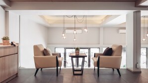 Una sala de estar moderna con dos sillones color beige, una mesita redonda e iluminación colgante.