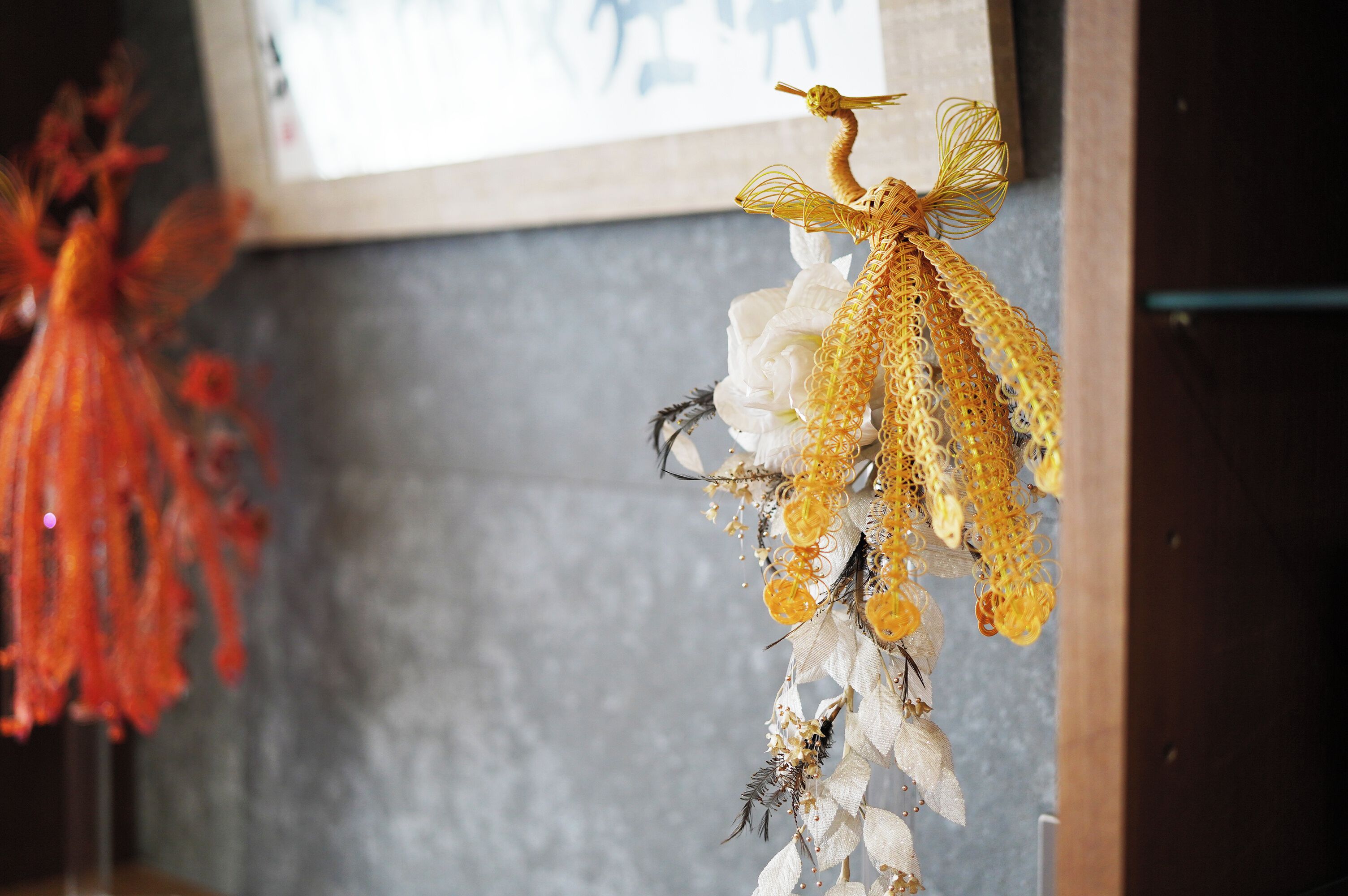 A wall with a framed picture and a decorative hanging ornament.