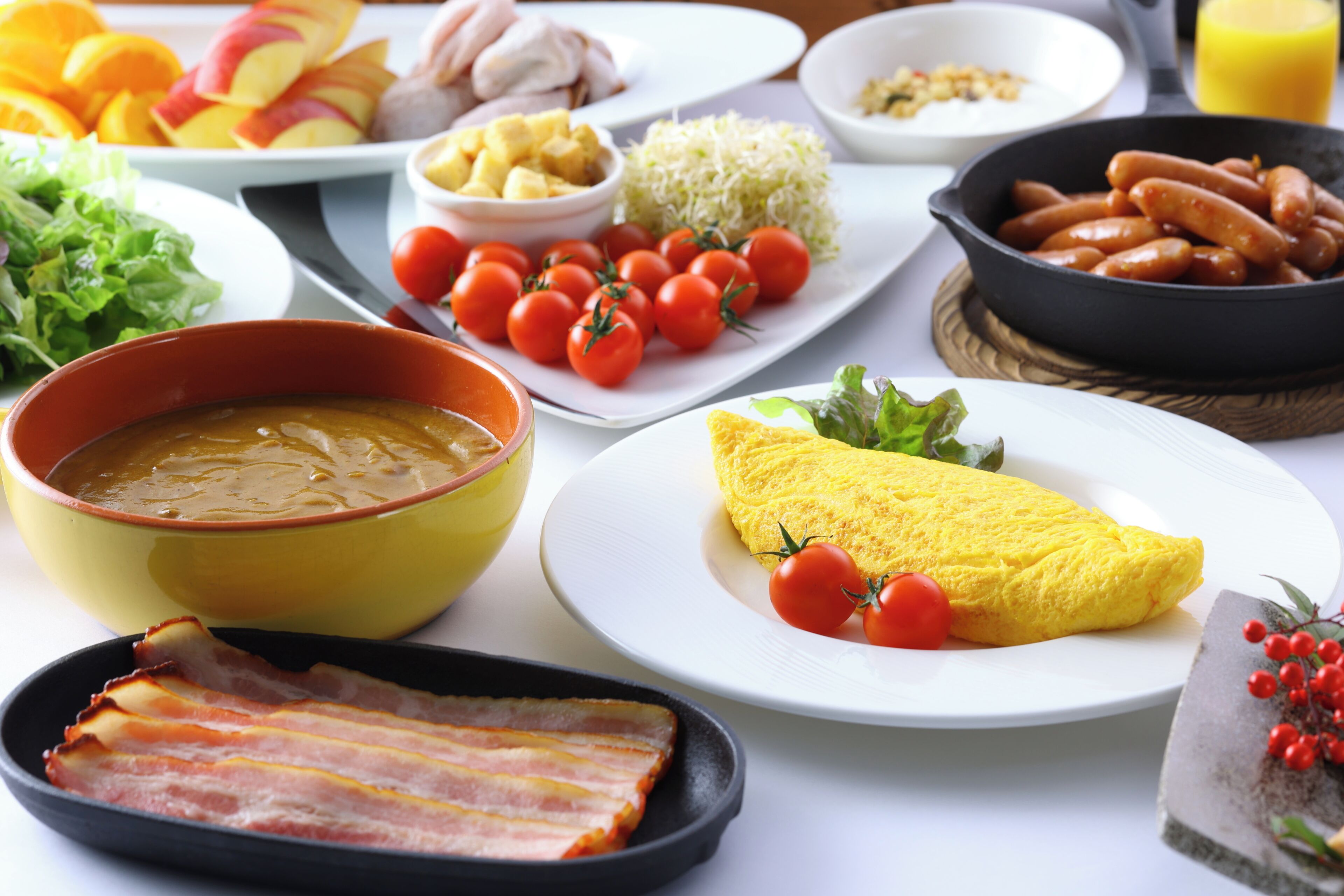 Un copieux petit-déjeuner composé de divers plats, notamment des œufs, du bacon, des tomates et des saucisses.