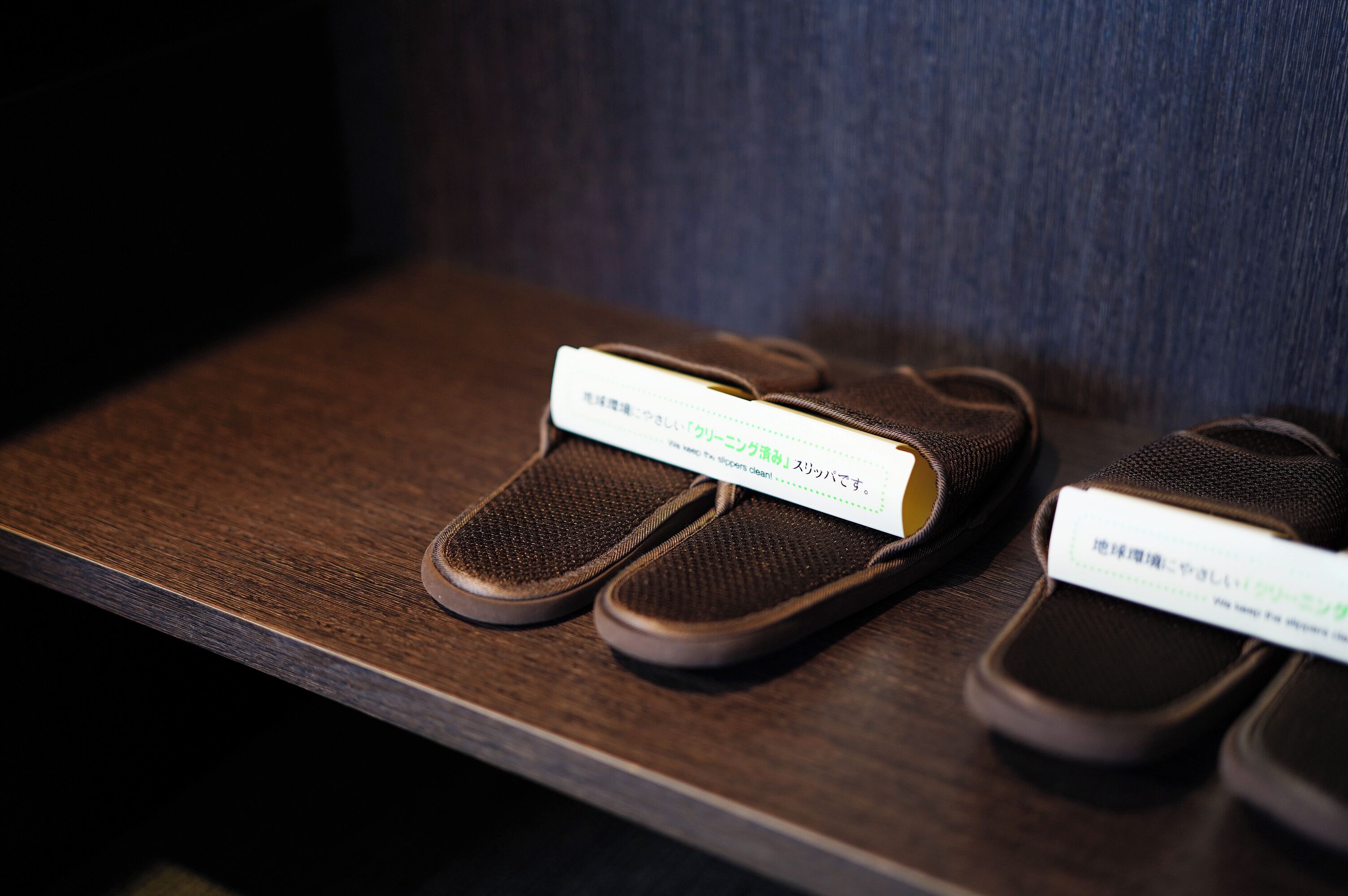 A pair of slippers with a label on a wooden surface.