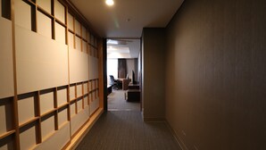 Un couloir doté d’une porte coulissante traditionnelle, d’un sol recouvert de moquette et, au fond, d’un bureau avec une chaise.
