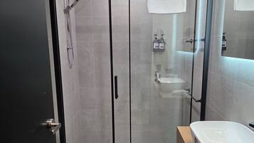A modern bathroom with a glass-enclosed shower, a white sink, and a toilet.