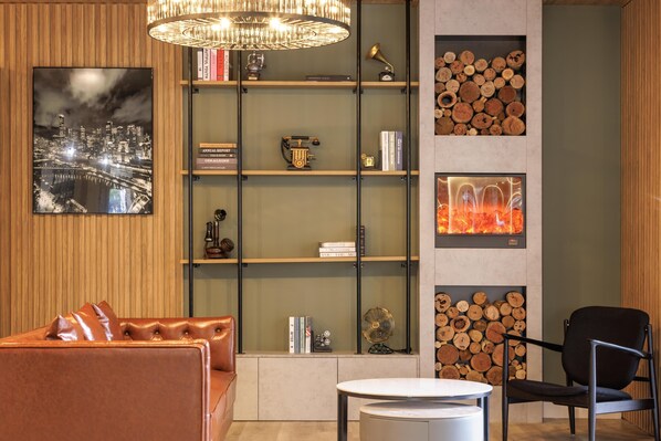 Uma sala de estar moderna com um sofá de couro, uma mesa redonda e uma estante com livros e objetos decorativos.