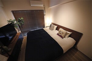 Una habitación de hotel con cama, escritorio y planta en maceta.