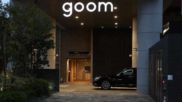 A building entrance with a 'goom' sign, a black car parked in front, and a sign reading 'BUSINESS ONE TENJIN'. - goom Hotel Nakasu (Fukuoka)
