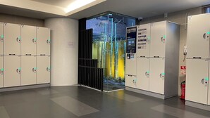 A modern hotel lobby with lockers, a pay station, and a glass door leading to an outdoor area. - goom Hotel Nakasu (Fukuoka)