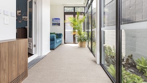 A hallway with a wooden cabinet, a blue sofa, and a potted plant. - The Albert Hotel Mosman (Mosman)