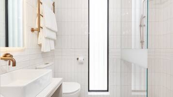 Un bagno moderno con lavandino, WC e zona doccia, tutto in bianco.