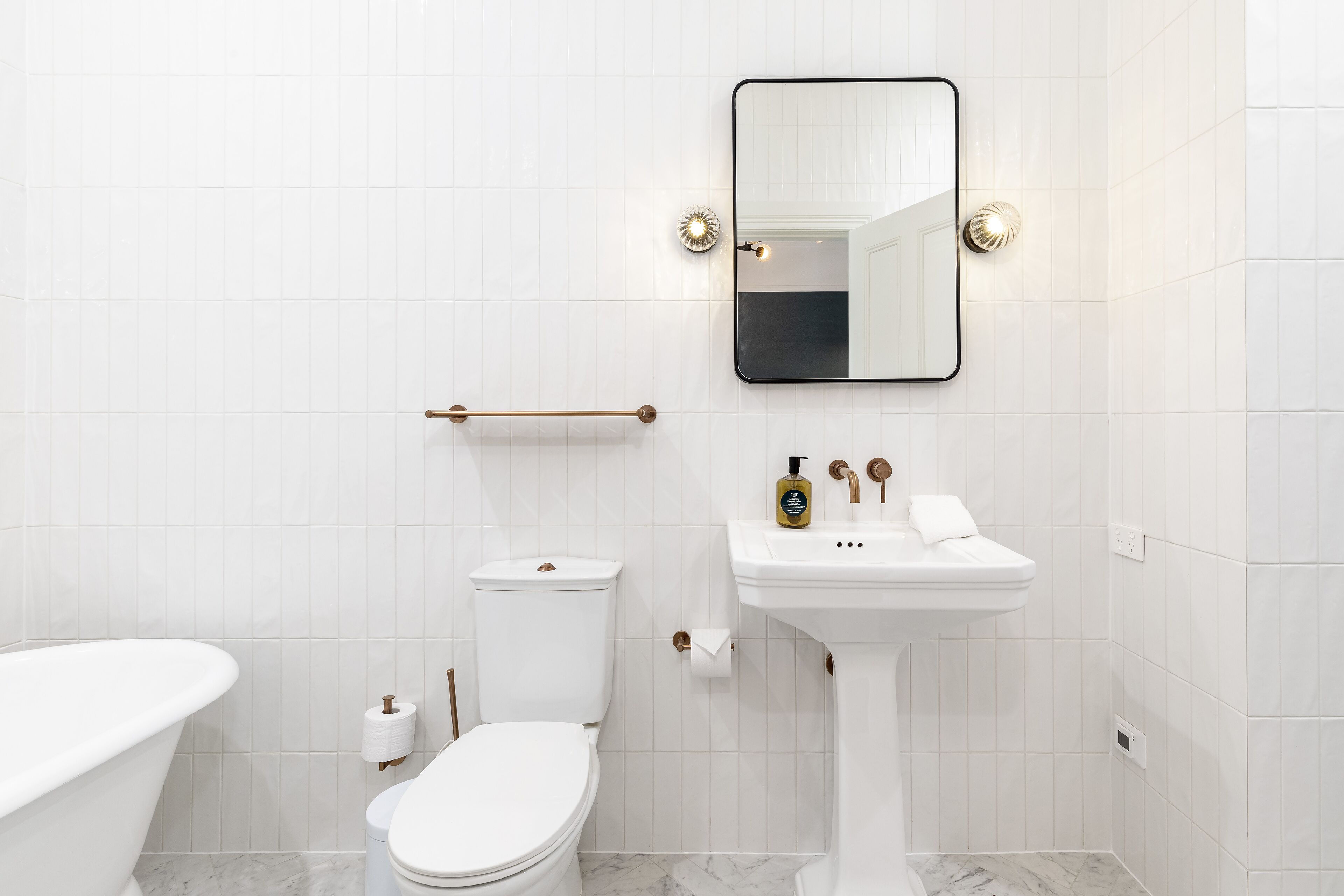 A modern bathroom with a freestanding bathtub, a toilet, a sink, and a mirror.