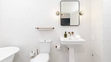 Un baño moderno con una bañera independiente, un inodoro, un lavabo y un espejo.