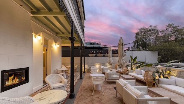 An outdoor patio with wicker furniture, a fireplace, and potted plants. - The Albert Hotel Mosman (Mosman)
