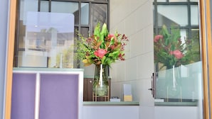 A reception area with a modern design, featuring a glass partition, a reception desk, and a vase with flowers. - The Albert Hotel Mosman (Mosman)