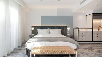 Una habitación de hotel moderna con una cama grande, mesitas de noche, un banco y un armario empotrado.