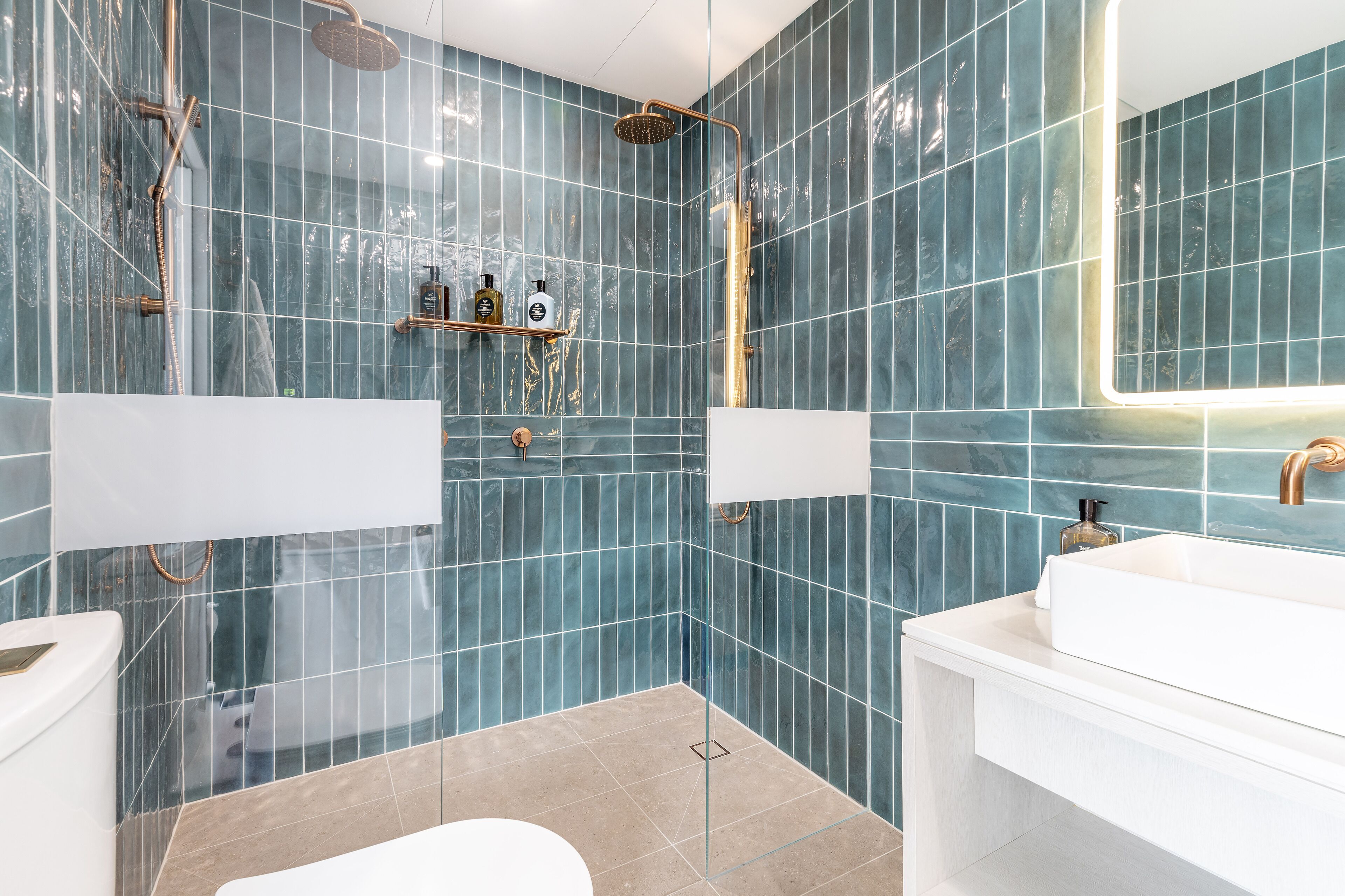 Un baño moderno con un espejo grande, dos lavamanos y una ducha.