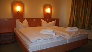 Habitación de hotel con una cama grande, dos lámparas fijadas a la pared, un cabecero de madera y una mesita de noche.